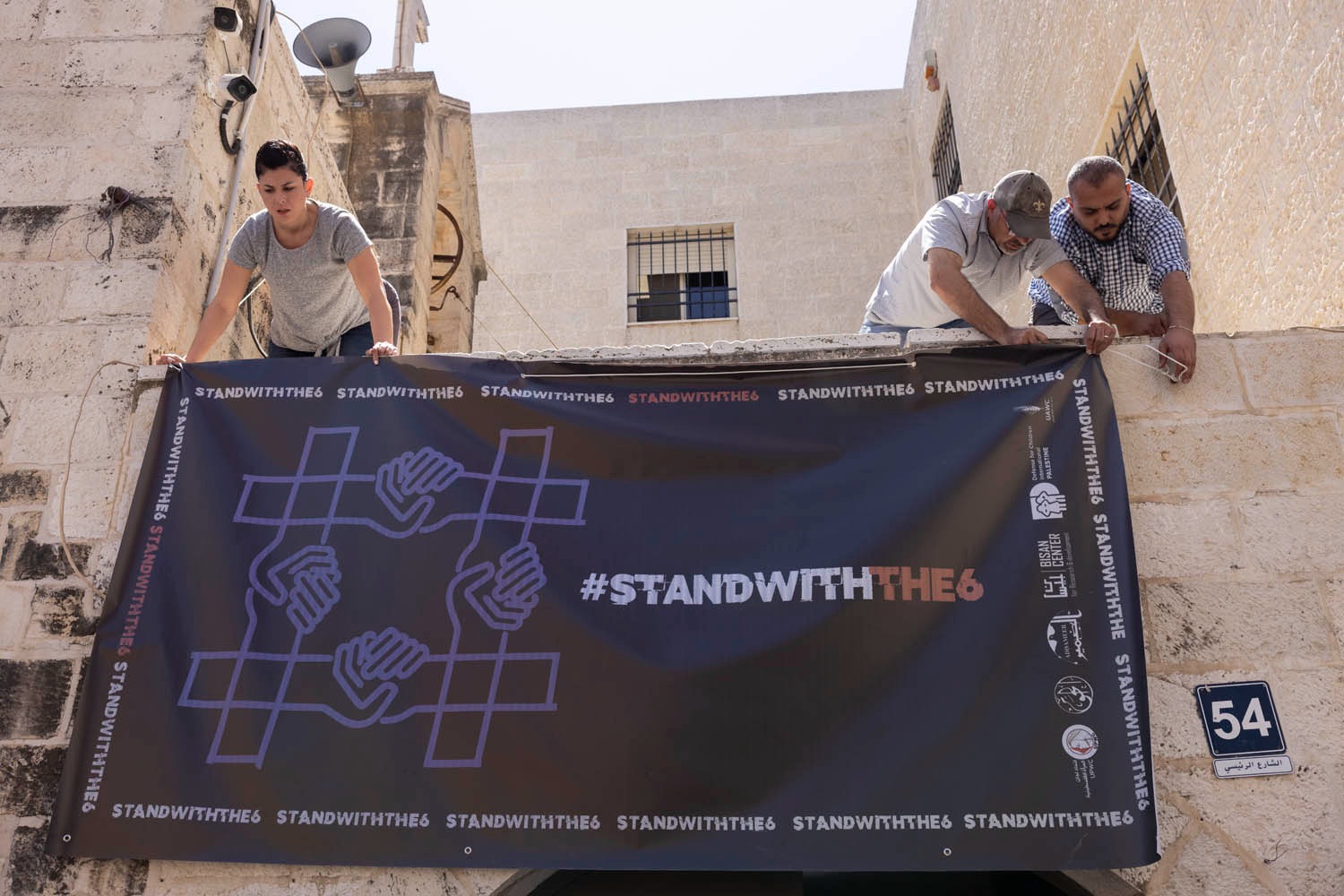 Ein Transparent zur Unterstützung der palästinensischen NGOs, die ins Visier genommen wurden, wird vor dem Gebäude von Al-Haq angebracht, nachdem die israelische Armee eine Razzia in ihren Büros durchgeführt hat, Ramallah, Westjordanland, 18. August 2022. (Oren Ziv)