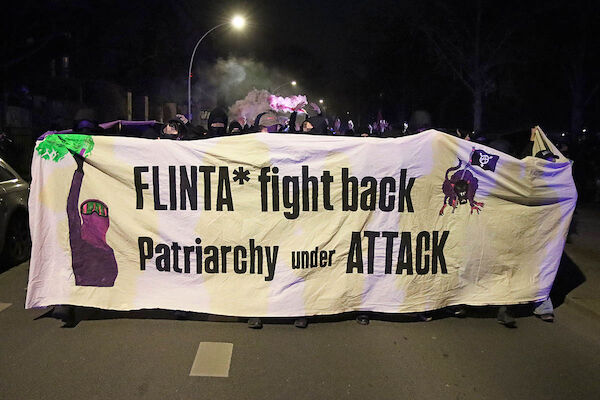 Fronttransparent mit dem Text: "Flinta* fight back - Patriarchy under attack" dahinter viele Menschen.