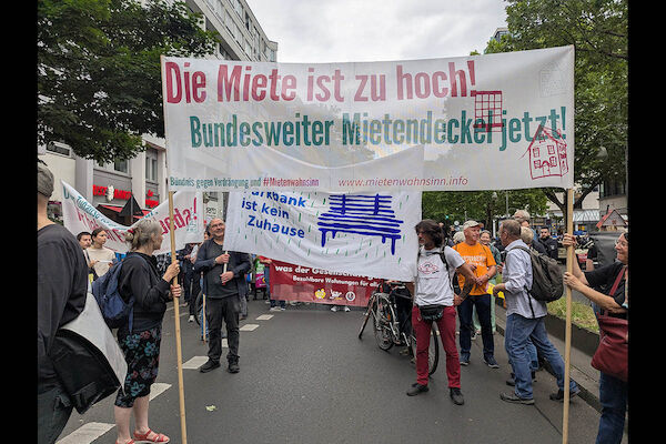 Das Foto zeigt einen Ausschnitt aus der Demontration während eines Stopps. Mehrere Transparente sind zu sehen, unter anderem eines mit der Forderung nach einem bundesweiten Mietendeckel.