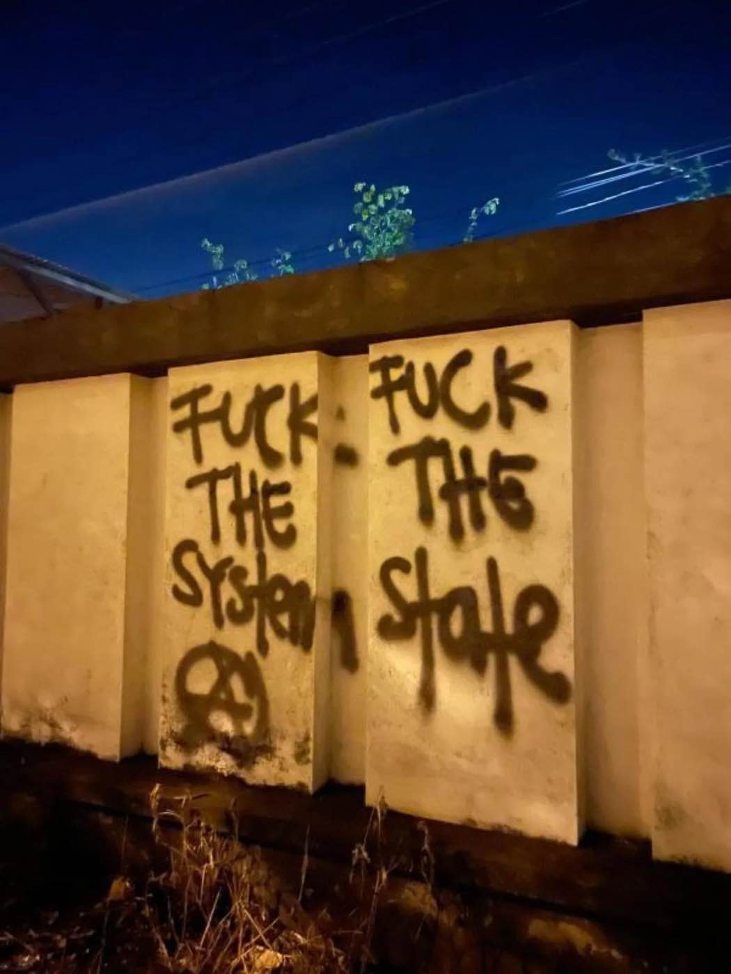 Graffiti mit dem Text "Fuck the System - Fuck the State" sowie dem Ⓐ an einer Mauer
