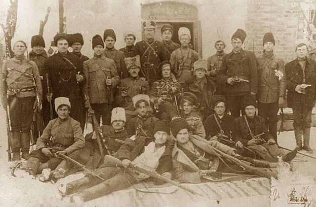 Das historische Foto zeigt eine Gruppe von Kämpfern der Anarchistischen Schwarzen Armee, angeführt von Fedir Schtschus, während des Ukrainischen Unabhängigkeitskriegs.Die Aufnahme stammt aus der Zeit zwischen 1918 und 1921. Die Gruppe, bekannt als die Dibriv-Abteilung, war Teil der Revolutionären Aufständischen Armee der Ukraine. Der Kontext ist der Ukrainische Unabhängigkeitskrieg und der Russische Bürgerkrieg.