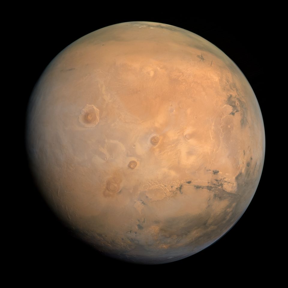 Der Mars in natürlichen Farben, aufgenommen von der al-Amal. In der Bildmitte ist der Tharsis Montes zu sehen, links davon der Olympus Mons und rechts das Valles Marineris.