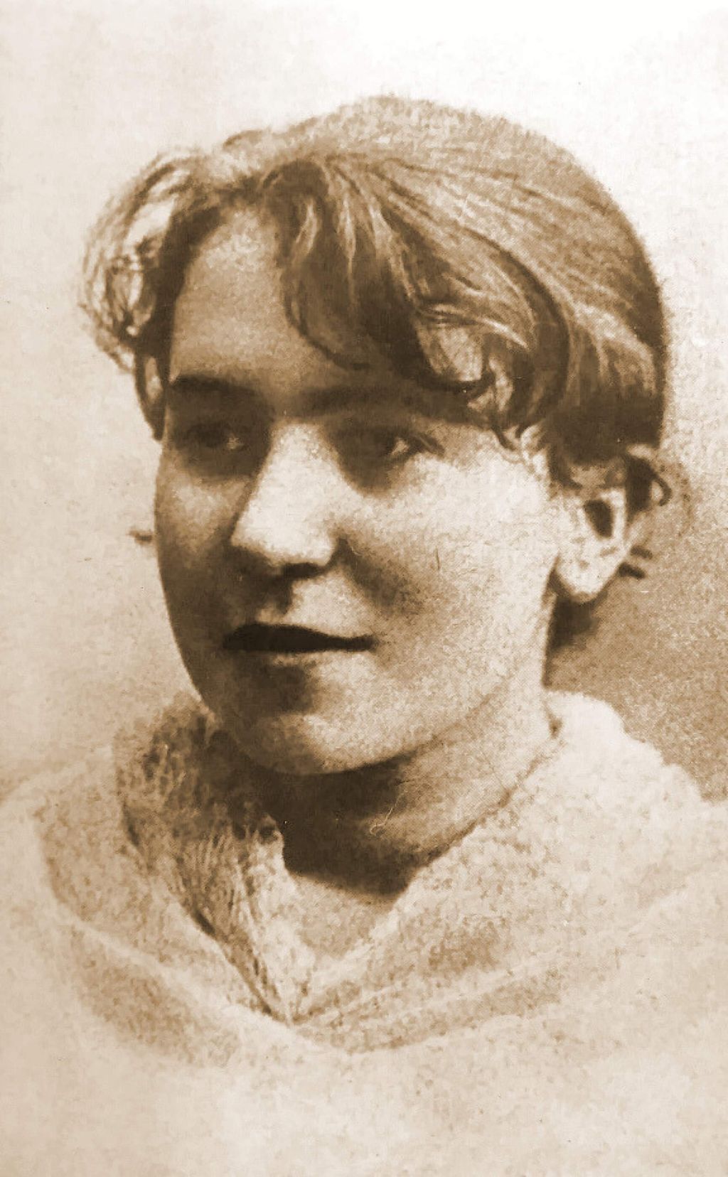 Historische, sepiafarbene Porträtfotografie der siebzehnjährigen Anarchistin und Frauenrechtlerin Emma Goldman aus dem Jahr 1886, als sie in Rochester in den USA ankam. Die Aufnahme zeigt sie als junge Frau mit kurzem, leicht gewelltem Haar, das in die Stirn fällt und seitlich zurückgesteckt ist. Sie trägt ein helles Kleidungsstück mit einem breiten, weichen Kragen. Ihr Kopf ist leicht zur Seite gedreht, ihr Blick wirkt ruhig und nachdenklich, mit einem angedeuteten Lächeln. Der schlichte, helle Hintergrund und die weichen Kontraste verleihen dem Porträt einen zurückhaltenden Charakter.