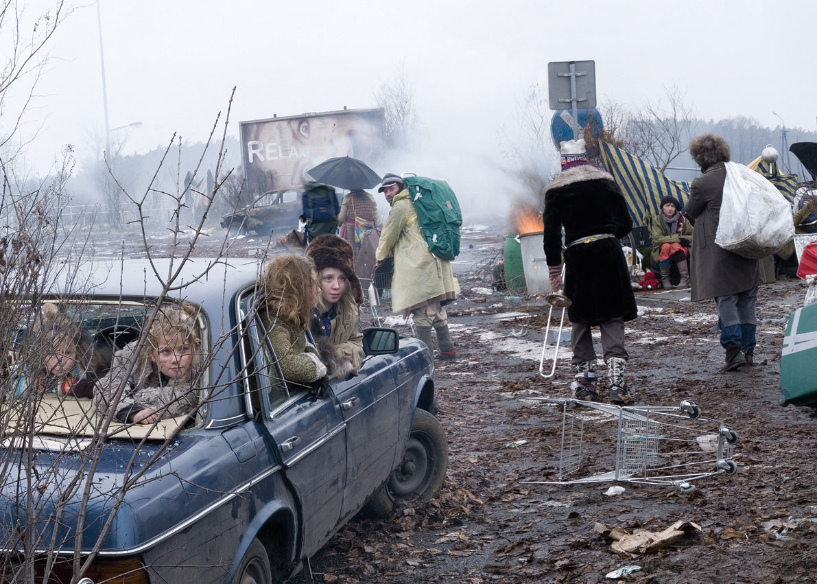 Das Bild zeigt den Exodus der Menschen aus den Städten. Zu sehen ist ein ramponierter alter Mercedes, in dem Kinder sitzen, drumherum eine Trümmer- und Müllwüste, Menschen, die ihre Habseligkeiten in Einkaufswägen transportieren und hoffnungslos in provisorischen Lagern sitzende Menschen.
